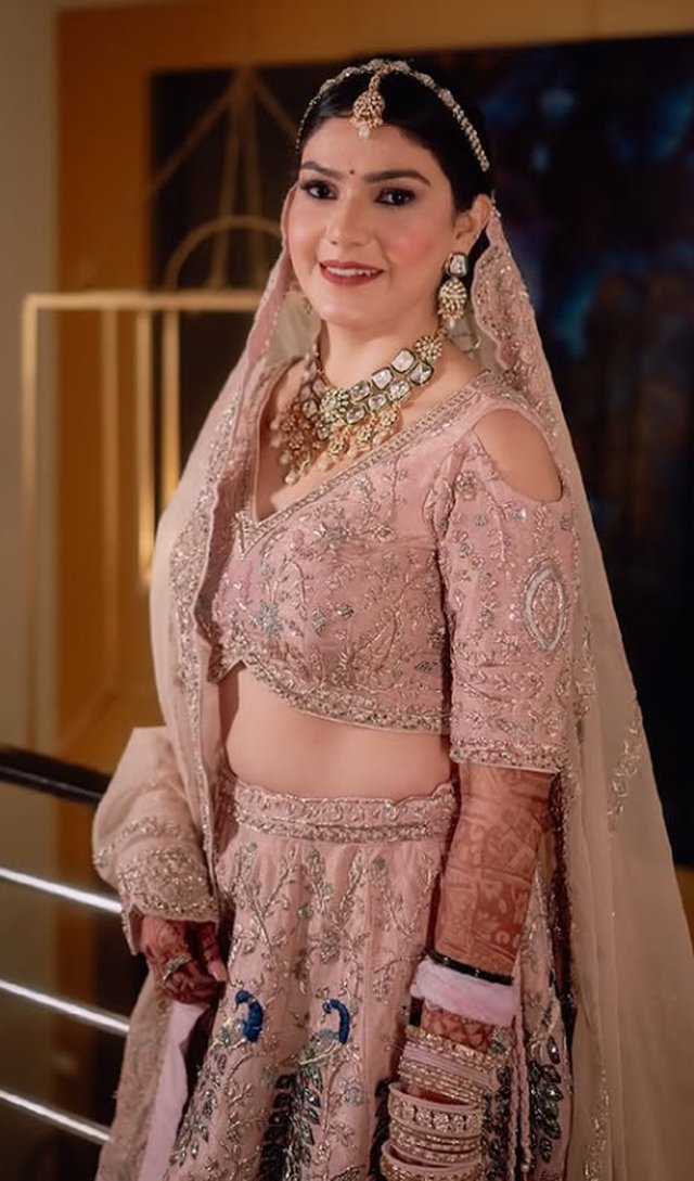 Bride in a blush pink reception lehenga with a polished, modern makeup look