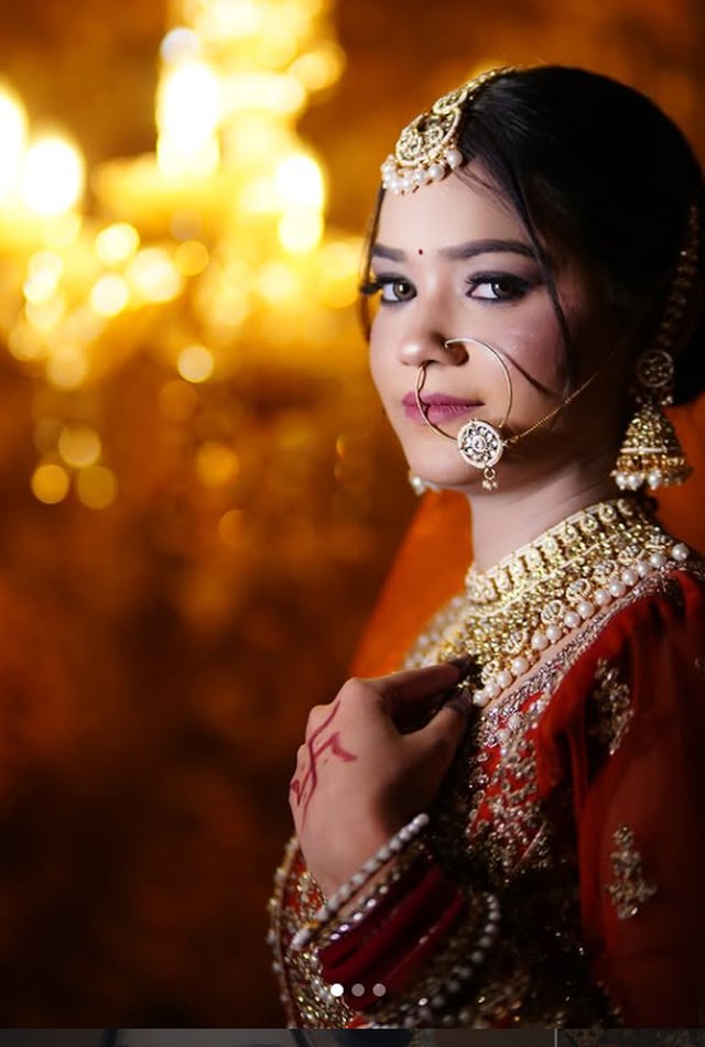 Glamorous red bridal makeup with golden bokeh lighting, suited to party and evening events