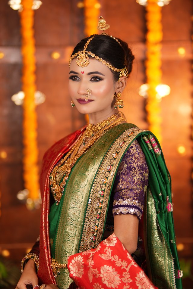 Bride in a green and gold traditional saree with temple-style jewellery, warm festive lighting