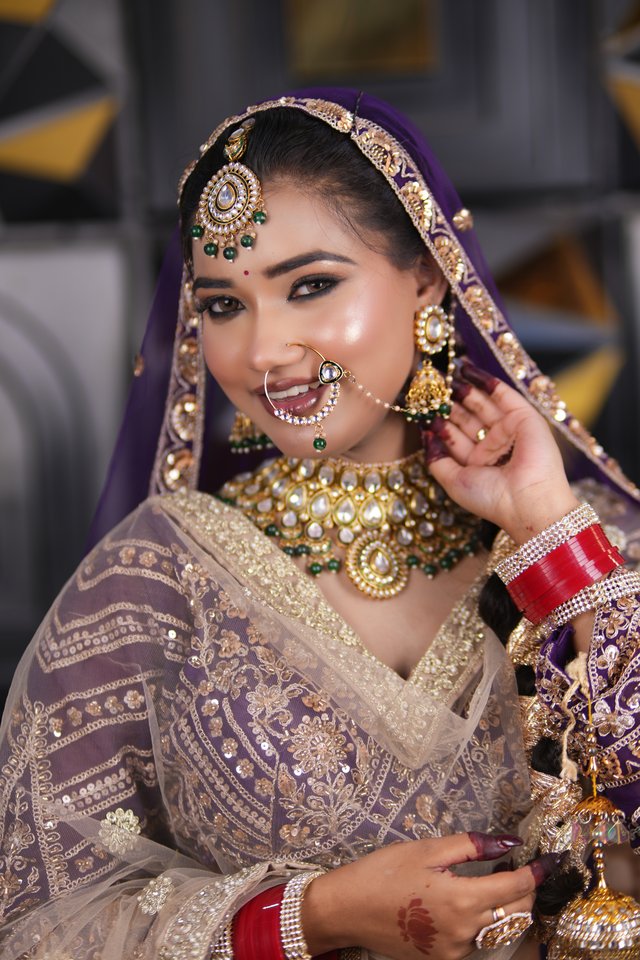 Bride in a purple and cream bridal lehenga with kundan jewellery, joyful bridal makeup look