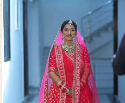 Apoorti on her wedding day, in a red and gold bridal lehenga